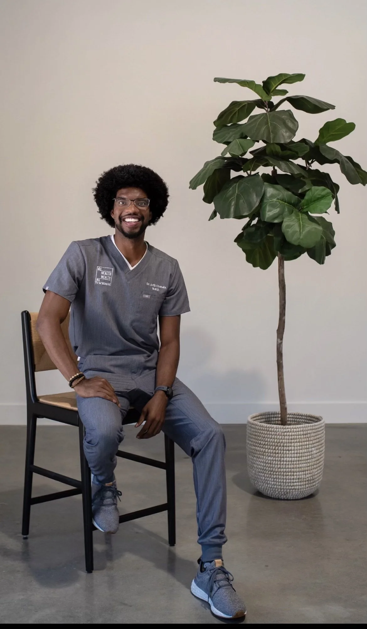 Dr. Ja’El seated beside a plant